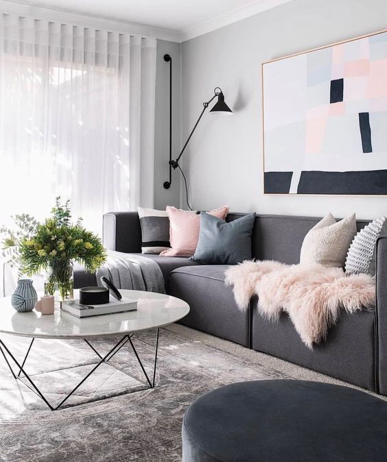 Aranżacja sofy w salonie z różowymi poduszkami i czarną lampą