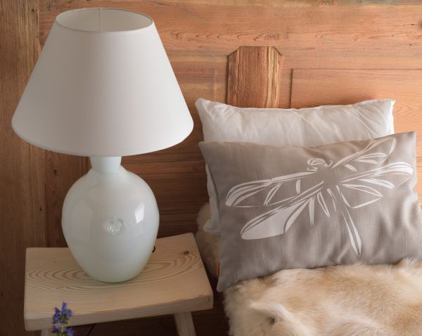 Biała lampa na stoliku przy łóżku w sypialni