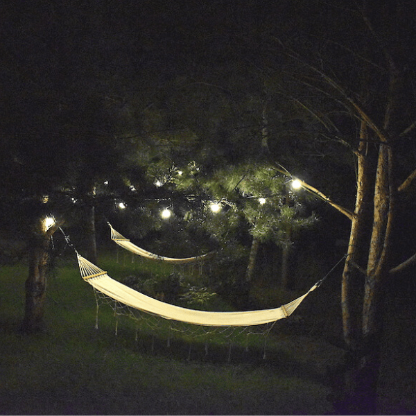 girlandy do ogrodu - nastrojowe oświetlenie drzew i hamaka