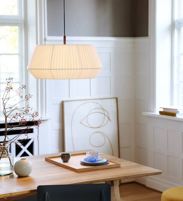 lampa wisząca z białym abażurem nad drewniany stół