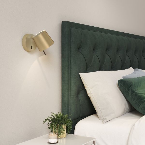 złoty kinkiet do sypialni z zielonym łóżkiem