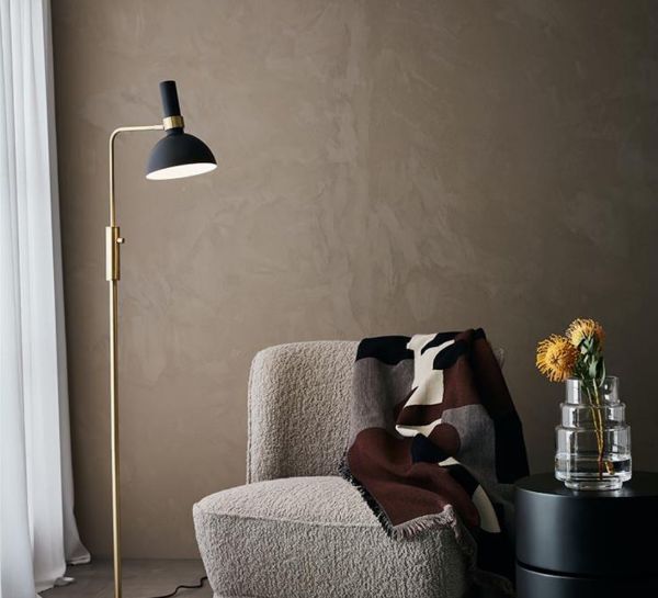 Lampa podłogowa przy fotelu na tle beżowej ściany