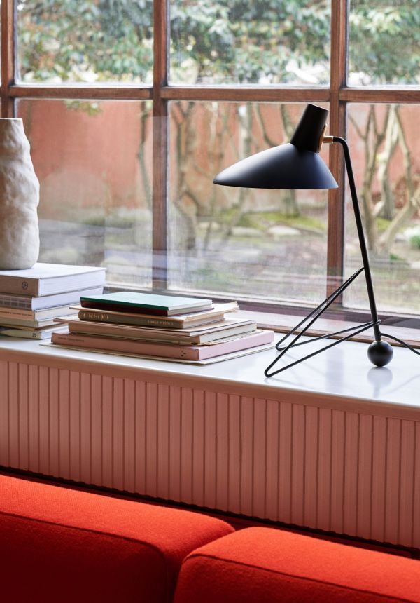 Czarna lampa biurkowa na parapecie przy oknie