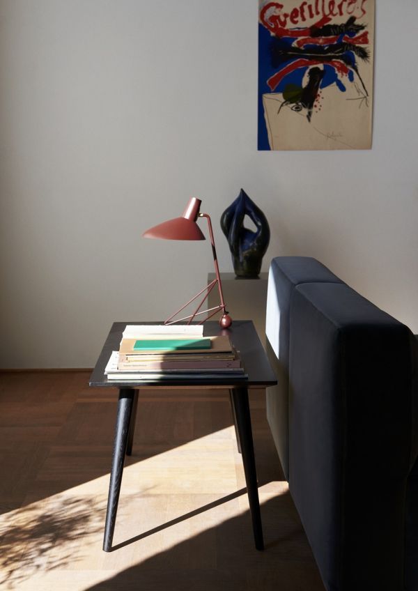 Nowoczesna lampa tripod na czarnym stoliku przy sofie