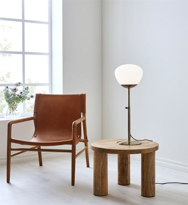 Lampa stołowa na drewnianym stoliku obok fotela