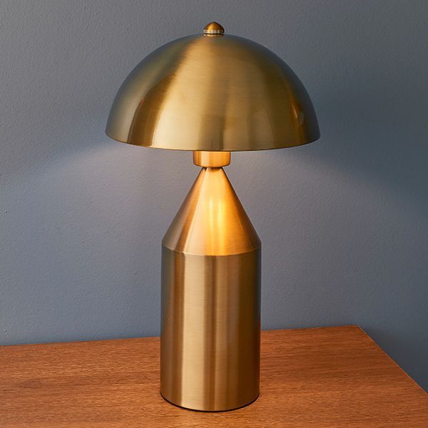 Lampa stołowa złota na drewnianej komodzie