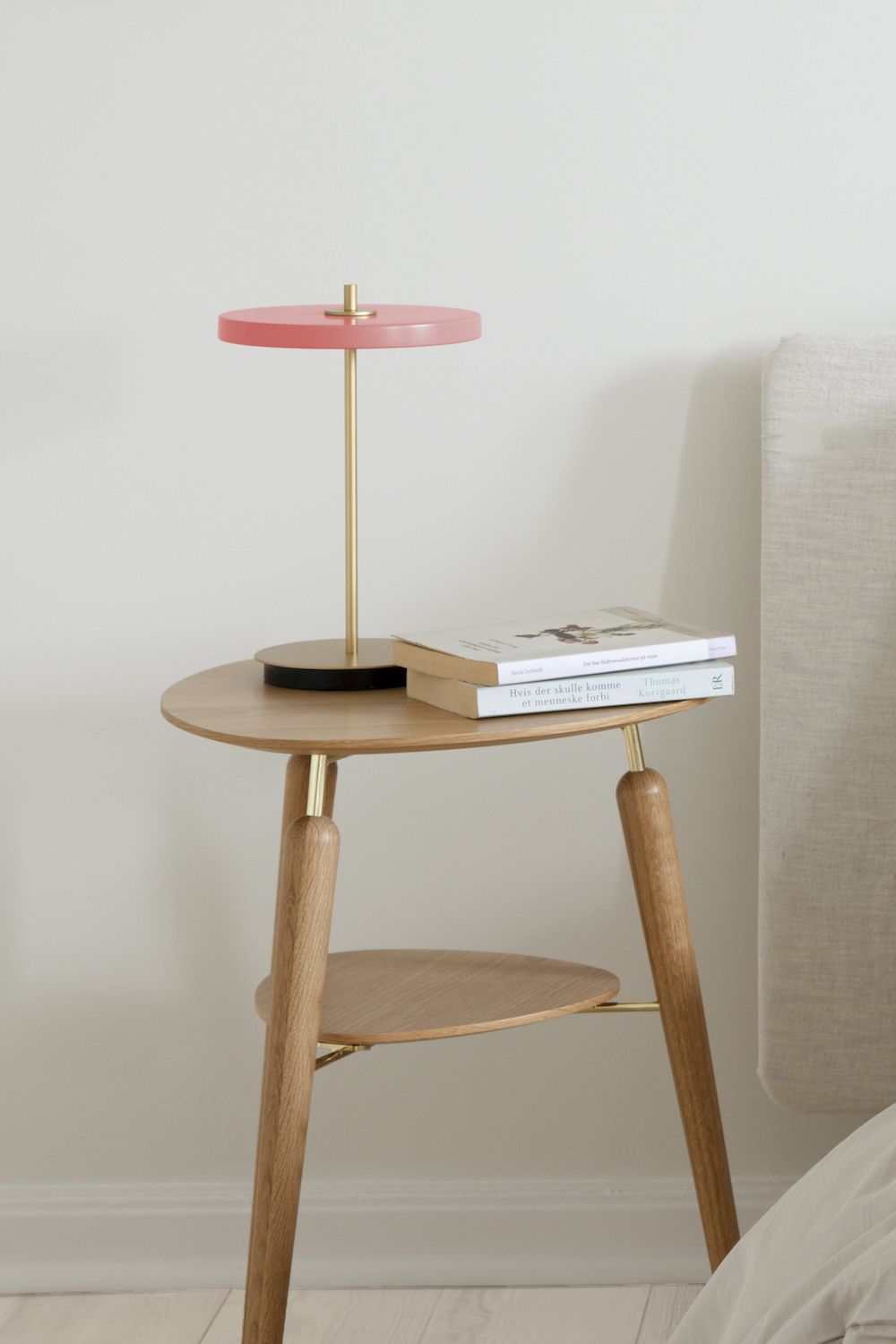 Lampa stołowa z różowym kloszem przy łóżku