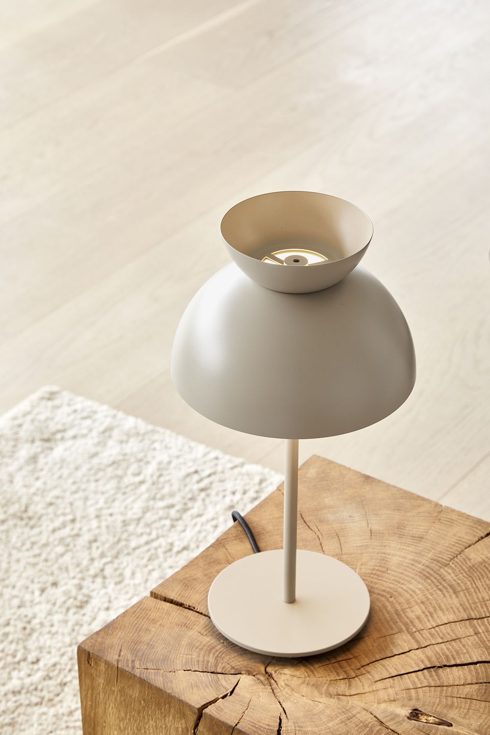 Lampa stołowa w kolorze szarobeżowym na drewnianym stoliku