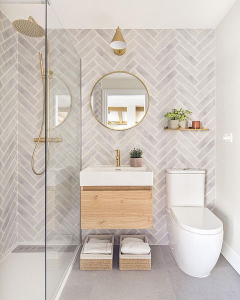 Jasno szara łazienka z płytkami imitującymi cegły ze złotymi lampami
