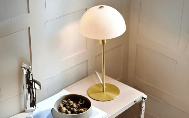 Złota lampa stołowa na komodzie