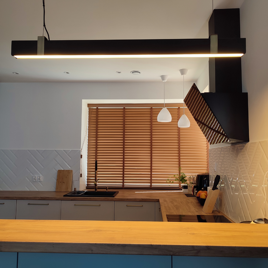 podluzna czarna lampa wisząca nad wyspę w kuchni