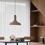 Beżowa metalowa lampa wisząca nad okrągły stół w salonie - drewniany detal