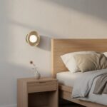 Beżowy okrągły metalowy kinkiet Ozzy nad szafke nocną do sypialni