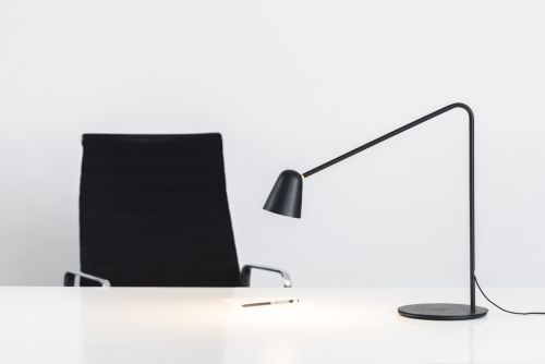 czarna lampa biurkowa z zakrzywioną podstawą, oryginalna, nowoczesna aranżacja
