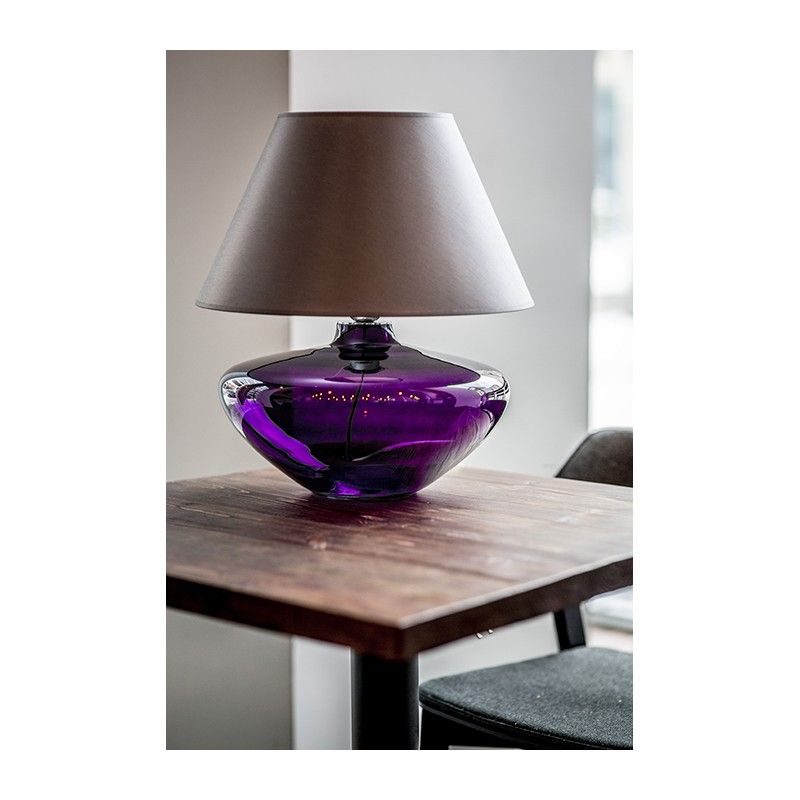 elegancka lampa stołowa ze szklaną podstawą w fioletowym kolorze i beżowym abażurem